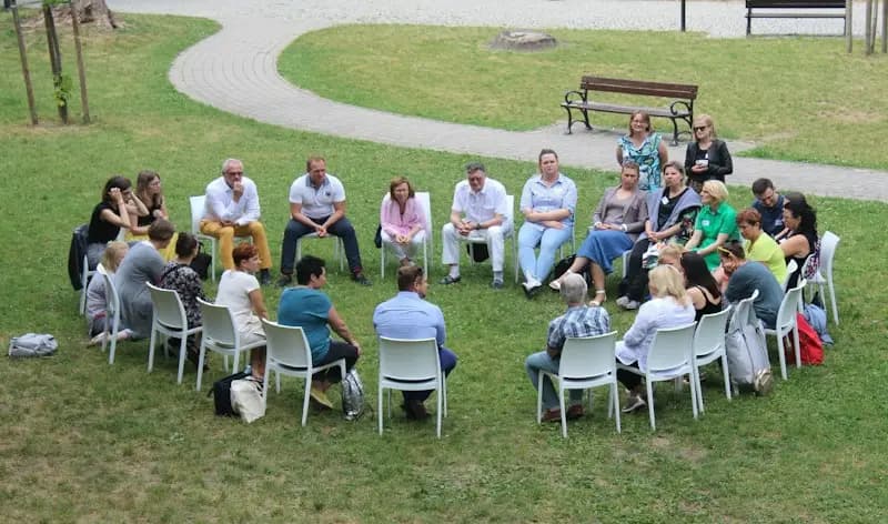 Grupo de pessoas sentadas em roda ao ar livre, em uma reunião comunitária